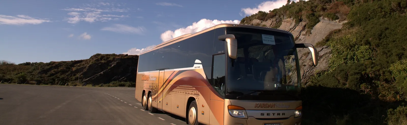 A Kardan Travel coach on a coastal road